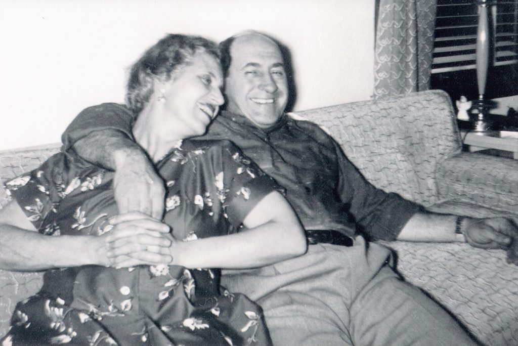 Ann and Paul Evangelist embracing on the couch.